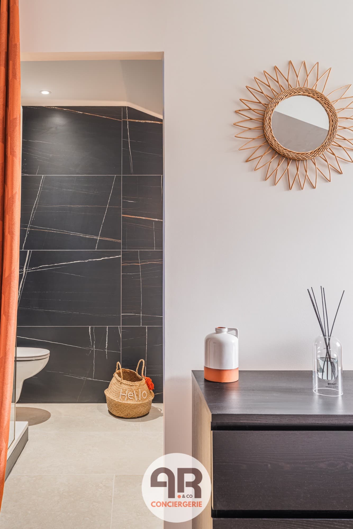 Intérieur d'un logement géré par AR&Co : miroir en rotin et salle d'eau en marbre